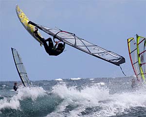 Wassersport in El Medano... ein Kiter macht ein Luping zwischen zwei Surfern